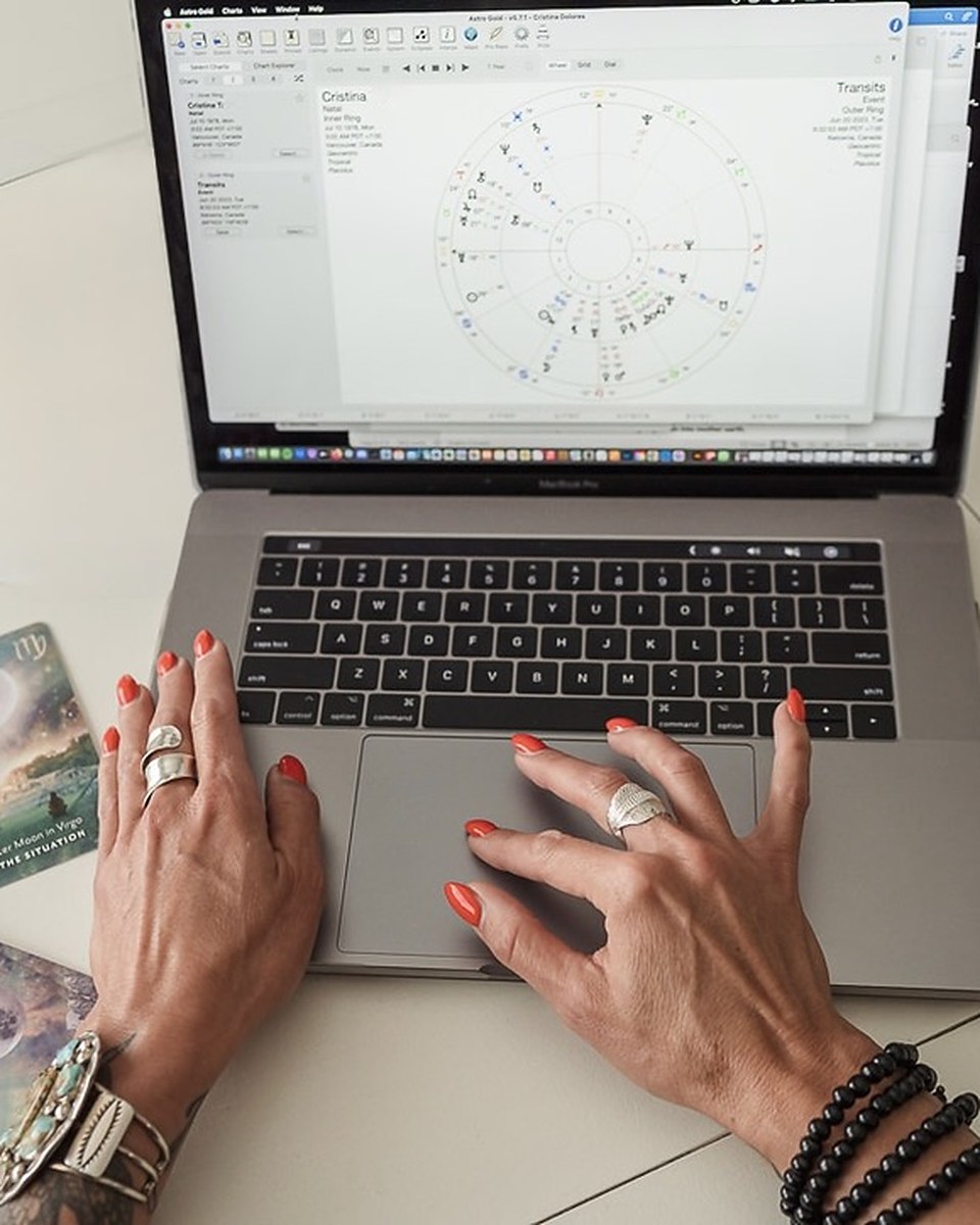 Reading a birth chart in Astro Gold, oracle cards beside the laptop